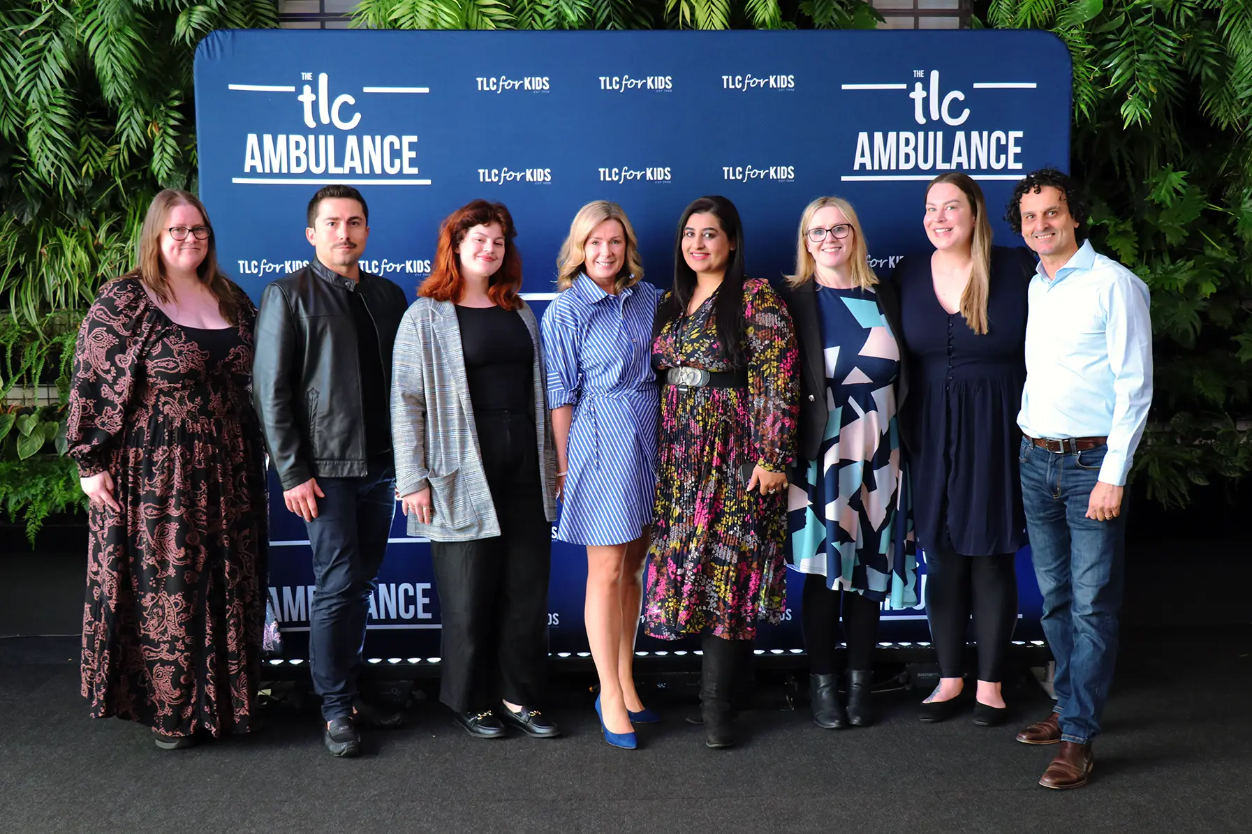 Guests at The Ambu-Lunch standing in front of a TLC Ambulance backdrop